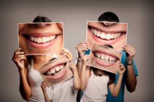 Family of four holding up photos of their teeth