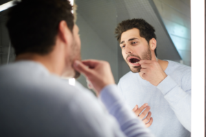 man looking at his tooth in mirror