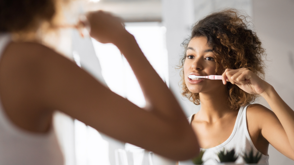 Woman Brushing Teeth in Mirror