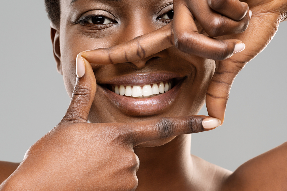 woman with white teeth framing her mouth with her hands